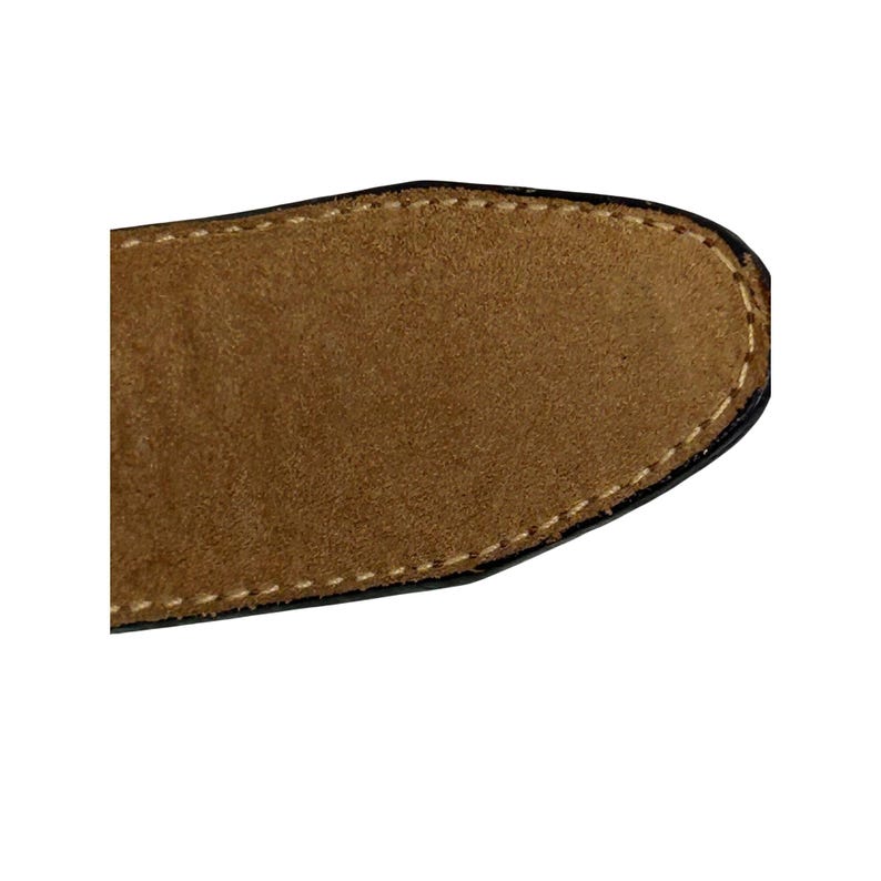 Puede incluir: Primer plano de una secci&oacute;n de un cintur&oacute;n de ante marr&oacute;n. El cintur&oacute;n tiene un borde negro con costuras blancas alrededor del borde del ante. El ante es de color marr&oacute;n claro.