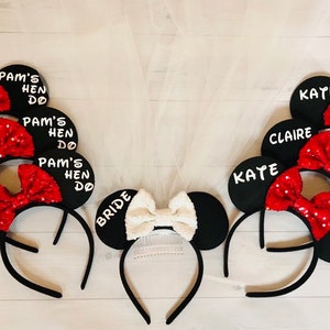 May include: Set of black and red mouse ears with white bows and text that says "Pam's Hen Do", "Bride", "Gillian", "Michelle", "Sylvia", "Kate", and "Claire".