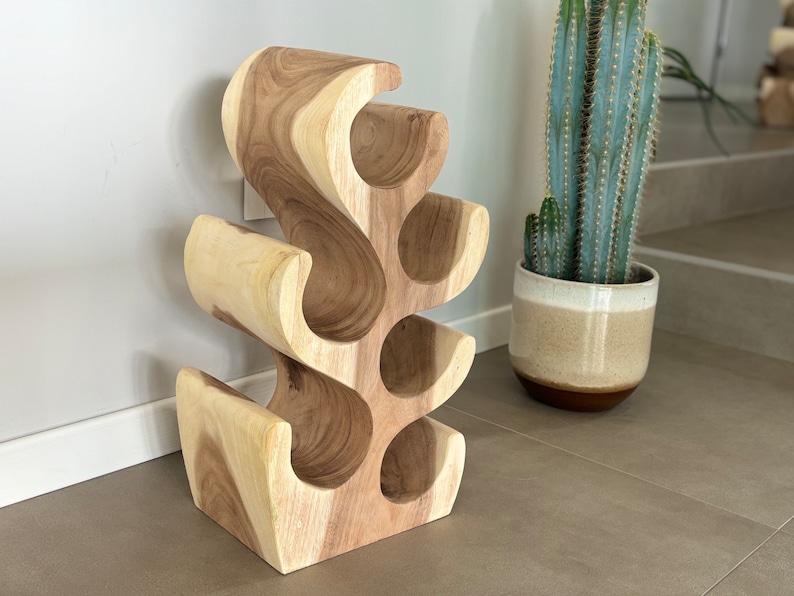 May include: A wooden wine rack shaped like a tree with six bottle holders. The rack is made of light brown wood and has a natural finish.