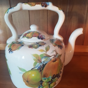May include: White ceramic teapot with a fruit design. The teapot has a handle and a lid. The fruit design includes pears, apples, and berries.