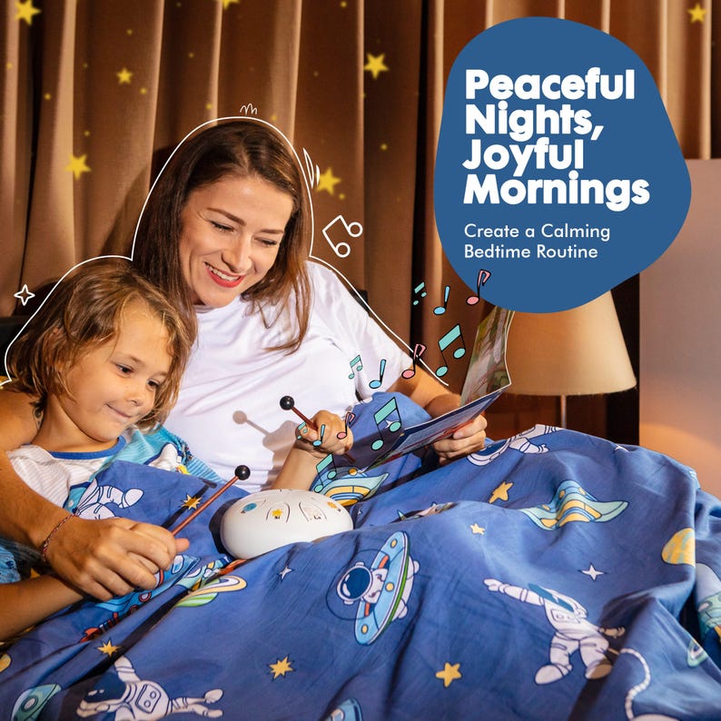 May include: A mother and child are in bed, reading a book and playing a handpan. The handpan is a circular, steel instrument with a hammered surface. The bedspread is blue with a space theme, featuring stars, astronauts, and spaceships. The text on the image reads "Peaceful Nights, Joyful Mornings. Create a Calming Bedtime Routine."