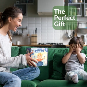May include: A woman smiles while presenting a personalized drum set to a child who is covering their eyes with their hands. The box features a colorful illustration of a child playing the drum with the text "Dylan's Dream Drum". The text "The Perfect Gift" is displayed in a green circle.