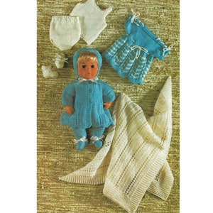 May include: A set of knitted doll clothes in white and blue. The set includes a dress, a coat, a hat, a pair of booties, a pair of trousers, and a vest.