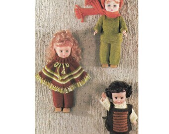Op de afbeelding: Drie gebreide poppenoutfits in verschillende kleuren en stijlen. De eerste outfit is een groene trui en broekset met een bijpassende muts en sjaal. De tweede outfit is een bruine poncho met groene strepen en franjes, gedragen met een bruine broek. De derde outfit is een bruin vest met oranje strepen, gedragen met een bruine broek.