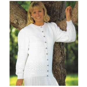 May include: White knitted cardigan with a button-up front and a delicate lace pattern. The cardigan has long sleeves and a relaxed fit.