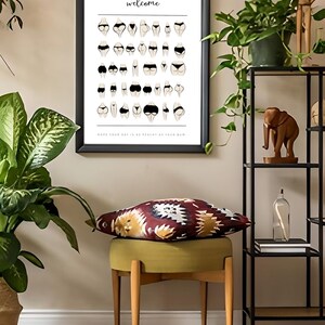 May include: A framed poster with the text "ALL BUMS welcome" and an illustration of various body types in underwear. The poster is hanging on a white wall above a green stool with a colorful patterned cushion.