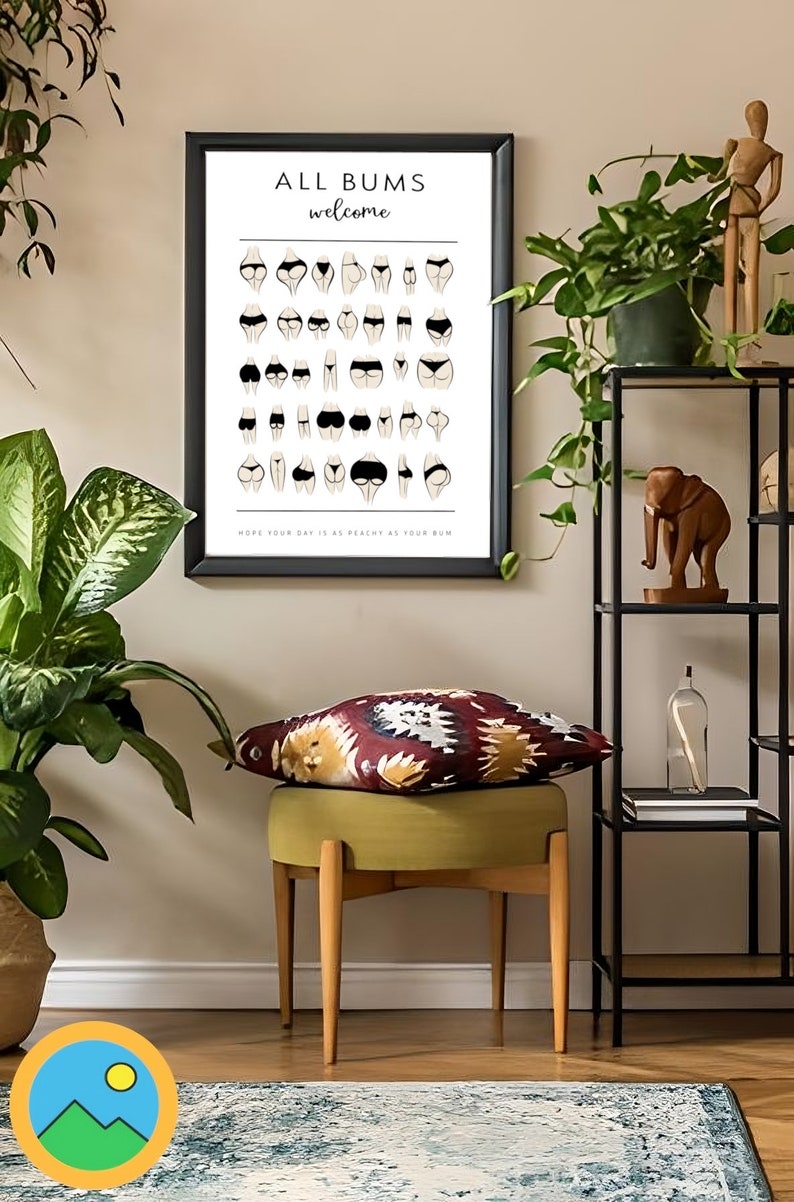 May include: A framed poster with the text "ALL BUMS welcome" and an illustration of various body types in underwear. The poster is hanging on a white wall above a green stool with a colorful patterned cushion.