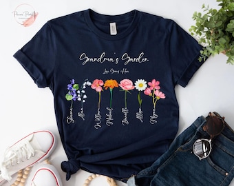 Può includere: Maglietta blu navy con il testo "Grandma's Garden" e un design floreale con sette fiori diversi con nomi sotto ogni fiore. I nomi sono: "Sharon", "Allan", "William", "Michael", "Danielle", "Allison" e "Myrna".