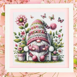 May include: A gnome wearing a pink and white crocheted hat sits in a white chair reading a book. The gnome is surrounded by pink and white flowers and butterflies.