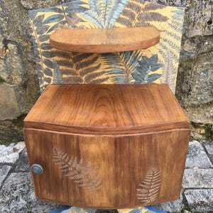 Vintage art deco style bedside table in varnished natural wood and fern decor