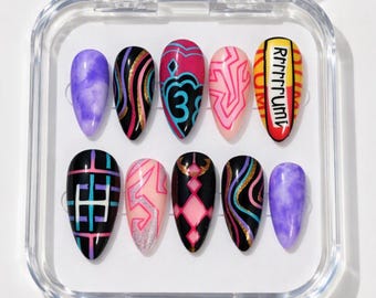 May include: A set of ten almond-shaped press-on nails in a clear plastic case. Designs include purple marble, black with gold and blue swirls, pink with blue patterns, pink with geometric lines, and yellow with the text RRRRRRUMI.
