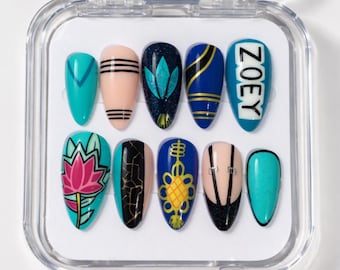 May include: A set of ten almond-shaped press-on nails in a clear plastic case. Designs include teal, nude with black stripes, dark blue with teal leaves, blue with gold lines, and one nail with the name ZOEY. Other nails feature a pink lotus, black crackle, yellow knot, and black corset-style lacing.