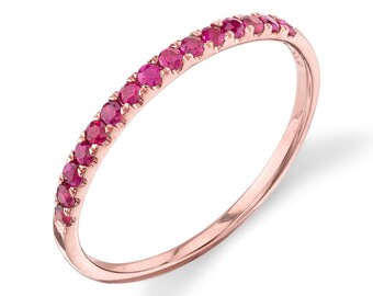 May include: A delicate rose gold band ring with a row of small, bright red ruby stones set along the top.
