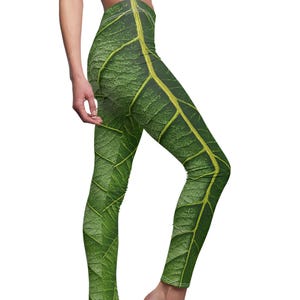 May include: Green leggings with a detailed leaf pattern, featuring shades of green and yellow. The leggings have a high waist and a close fit, mimicking the texture and veins of a leaf. The design creates a natural, botanical aesthetic.