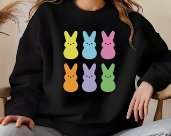 Peut inclure: Sweat-shirt noir avec un motif coloré de six lapins en pastel. Les lapins sont disposés en deux rangées de trois.