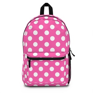 May include: A pink backpack with a white polka dot pattern. The backpack has a zippered front pocket and adjustable straps.