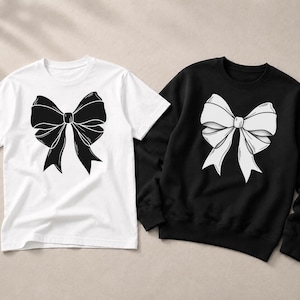 Könnte beinhalten: Ein weißes Kurzarm-T-Shirt mit einer großen schwarzen Schleifengrafik auf der Brust, platziert neben einem schwarzen Langarm-Sweatshirt mit einer großen weißen Schleifengrafik auf der Brust. Beide Kleidungsstücke haben einen Rundhalsausschnitt.