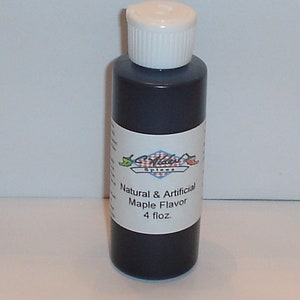 May include: A small, dark brown glass bottle with a white cap. The bottle contains maple flavoring. The label reads "Natural & Artificial Maple Flavor 4 fl.oz."