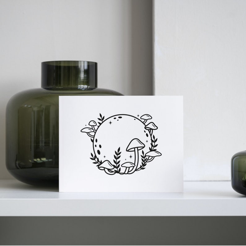 May include: A black and white illustration of a moon with mushrooms growing around it. The moon has a dotted pattern and stars around it.