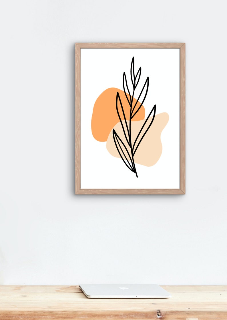 May include: A framed print with a minimalist design featuring a black line drawing of a leaf with two orange and peach abstract shapes behind it.