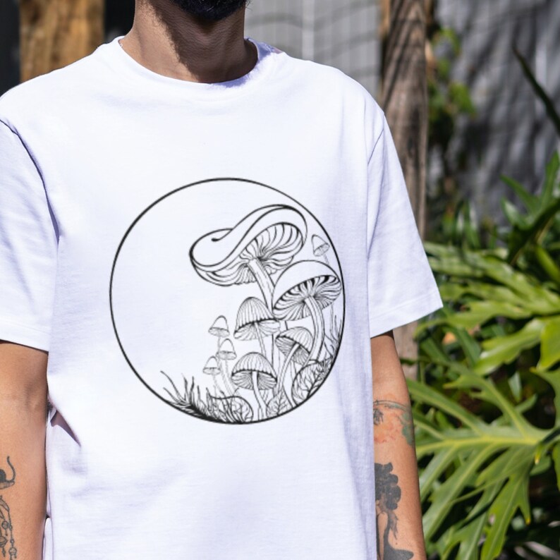 Op de afbeelding: Wit T-shirt met een zwart-witte illustratie van paddenstoelen in een cirkel op de voorkant.