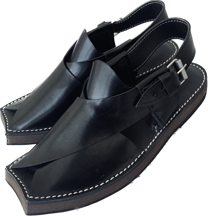K&ouml;nnte beinhalten: Schwarze Ledersandalen mit Schnallenriemen und einem gen&auml;hten Rand. Die Sandalen haben eine spitze Zehenpartie und eine flache Sohle.