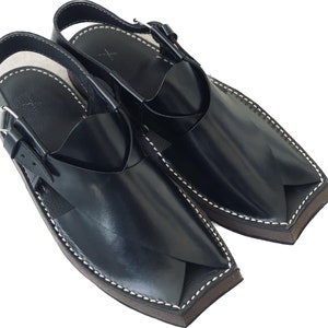 K&ouml;nnte beinhalten: Ein Paar schwarze Ledersandalen mit spitzer Zehenpartie und einem Riemen &uuml;ber dem Fu&szlig;r&uuml;cken. Die Sandalen haben einen wei&szlig;en N&auml;hdetail an den R&auml;ndern.