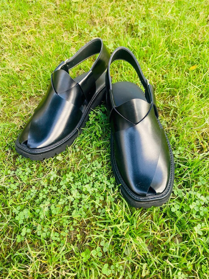 May include: A pair of black leather sandals with a criss-cross strap design. The sandals have a closed toe and a thick sole.