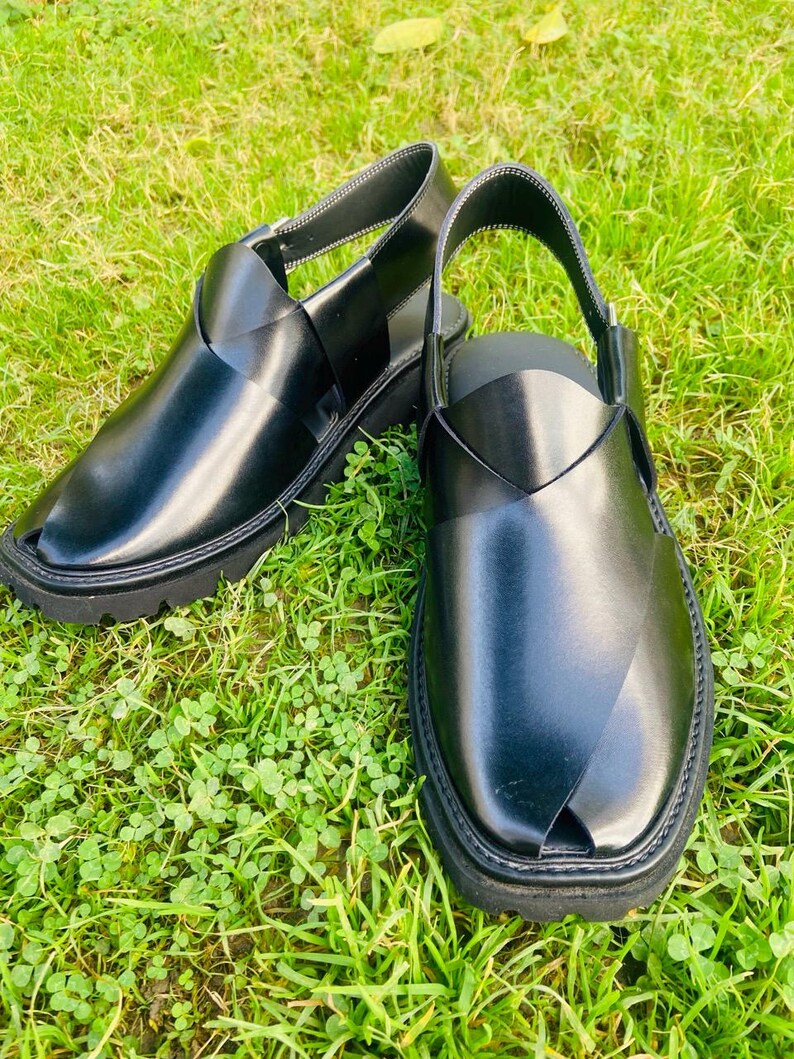 May include: A pair of black leather sandals with a criss-cross strap design. The sandals have a closed toe and a thick, black sole.