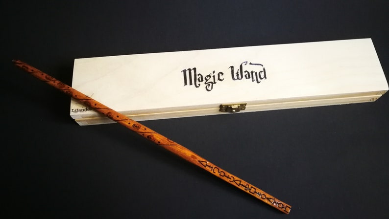 May include: A wooden wand with intricate carvings and a wooden box with the words "Magic Wand" printed on it.