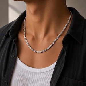 Op de afbeelding: Een zilverkleurige touwketting met een gedraaid, getextureerd metalen ontwerp. De ketting rust rond de hals en toont een doorlopend, uniform schakelpatroon dat een spiraalvormig uiterlijk creëert over de gehele lengte van het sieraad.