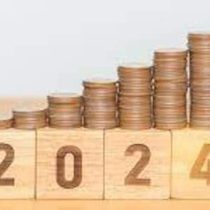 May include: A wooden block with the number 2024 on it.  Each number is on a separate block.  Each block has a stack of coins on top of it, with the stack getting taller for each number.  The coins are arranged in a stair-step pattern.