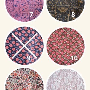 May include: Six circular fabric swatches featuring various patterns: 7 is pink with dark blue celestial icons, 8 is black with gold celestial motifs, 9 and 10 show pink flowers on dark backgrounds, 11 has a dense floral print, and 12 features white ferns.