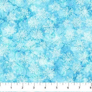 May include: A fabric with a blue and white snowflake pattern. The snowflakes are white and vary in size, scattered across a light blue background. The fabric is measured with an 8-inch ruler.