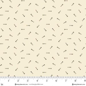 May include: Cream-colored fabric with a repeating pattern of small, dark gray squares and dots. The squares and dots are arranged in a scattered, diagonal layout. The fabric has a ruler along the bottom edge, with measurements in inches.
