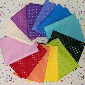 May include: A collection of colorful fabric squares arranged in a circular pattern. Each square is a different color, including pink, red, orange, yellow, green, black, teal, blue, and purple. The fabric has a polka dot pattern with white dots.