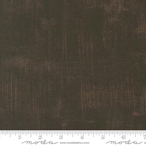 May include: Dark brown fabric with a distressed, textured appearance. The fabric has vertical and horizontal scratch-like markings in a lighter brown color, creating a worn, vintage aesthetic. The fabric is suitable for quilting and other craft projects.