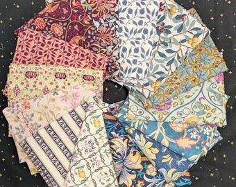 May include: A circular arrangement of fabric squares with various floral and botanical patterns. The fabrics feature a range of colors, including burgundy, pink, blue, and yellow, with detailed designs of flowers, leaves, and fruits. The fabrics are arranged on a black surface.