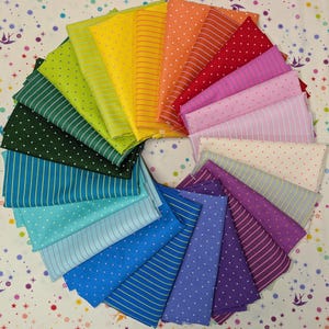 May include: A vibrant array of folded fabric squares arranged in a circular pattern, showcasing a spectrum of colors from green to purple. The fabrics feature various patterns, including stripes and polka dots, creating a visually appealing display.