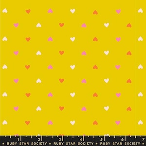 May include: Mustard yellow fabric with a repeating pattern of small hearts in white, pink, and red. The fabric has a smooth texture and is suitable for various sewing projects. The text "RUBY STAR SOCIETY" is printed at the bottom.