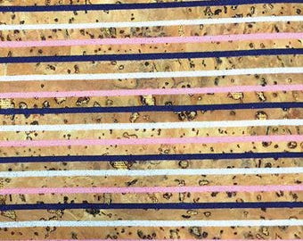 May include: Close-up of a patterned surface with horizontal stripes. The design features alternating stripes of light brown, white, pink, and navy blue. The light brown stripes have a textured appearance with dark spots.