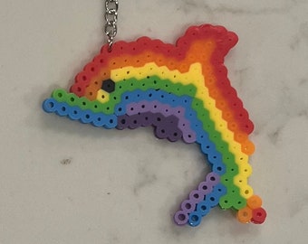 Puede incluir: Llavero de delfín de cuentas de colores arcoíris. El delfín está hecho de pequeñas cuentas de plástico en un patrón de arcoíris. El llavero tiene un anillo y una cadena de metal plateado.