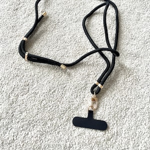 May include: Black lanyard with a gold clasp and a black rectangular name tag.