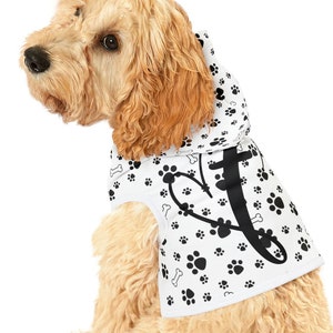 May include: A white dog hoodie with a black paw print and bone pattern. The hoodie has a hood and a black heart with a bone design.