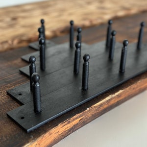 Puede incluir: Perchero de metal negro con múltiples ganchos montado en una superficie de madera.