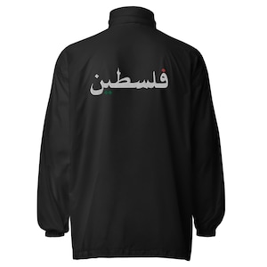Op de afbeelding: Zwarte jas met een hoge kraag en lange mouwen. De achterkant van de jas is voorzien van het Arabische woord "Palestina" in het wit, met rode en groene accenten. De jas heeft een volledige ritssluiting en een eenvoudig, klassiek ontwerp.
