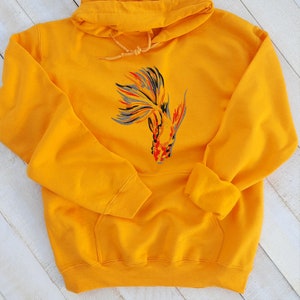 Peut inclure: Un sweat &agrave; capuche jaune avec une image brod&eacute;e d'un poisson rouge color&eacute; sur le devant.