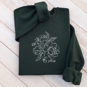 May include: A dark green sweatshirt with a white outline of a bouquet of peonies and the word "peony" written underneath.