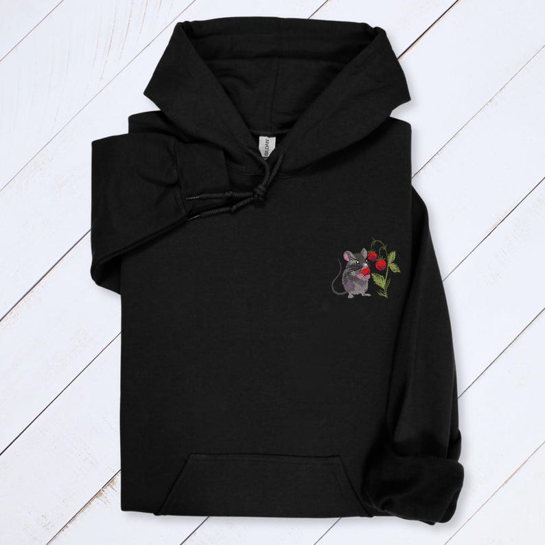 May include: Black hooded sweatshirt with a kangaroo pocket. The sweatshirt features a small embroidered design of a gray mouse holding red berries and green leaves on the left chest. The hoodie has a drawstring and a hood.