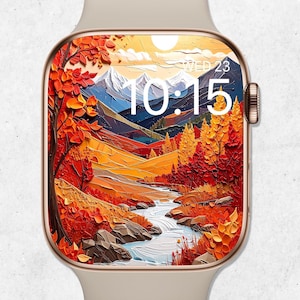 May include: A beige smartwatch with a gold-colored frame displays a vibrant autumn landscape. The screen shows a river winding through a valley with colorful trees and mountains. The time is 10:15, and the date is Wednesday, September 23.